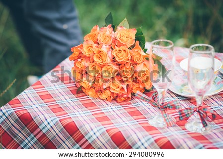 A bouquet of orange and pink flowers with two wine goblets lying on a wedding table