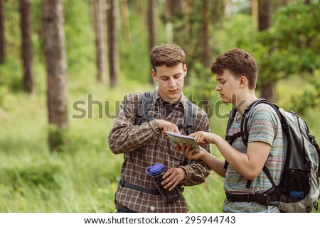 two young tourist determine the route map and compass