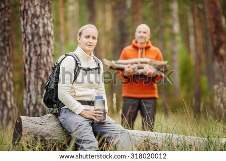 Beautiful young woman hiking happy with water bottle in front of forest