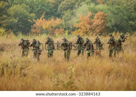 group of soldiers running across the field and shoot