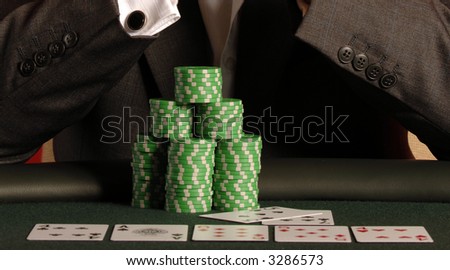 A poker player has a full house and chips on the table while gambeling.