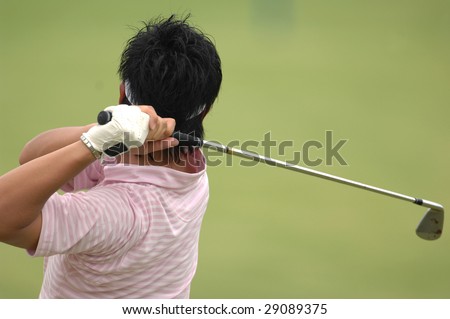 A male golfer hits a ball and is in his back swing.