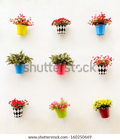 Artificial colorful flowers pots hang onto the wall