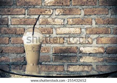 iced coffee on glass table with brick wall background.
