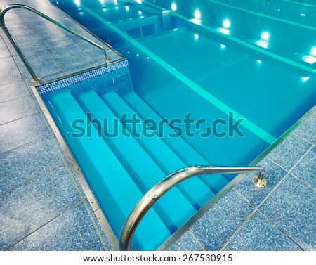 Staircase with handrails into the pool with blue water