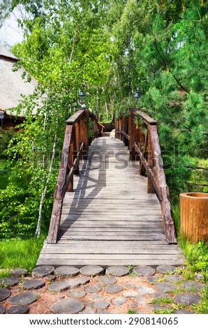 Wooden bridge over the ravine among the trees and pines