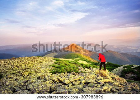 Photographer taking pictures on a hill mountaintop lit red