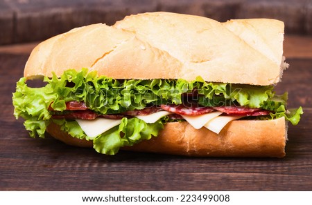 Sandwiches - turkey breast, ham & swiss and salami on old cutting board.