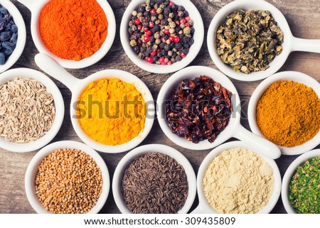 Spices and herbs in ceramic bowls on wooden background . Traditional Indian food .