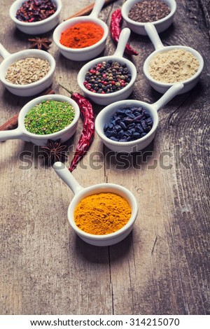 Spices and herbs in ceramic bowls on wooden background . Traditional Indian food .