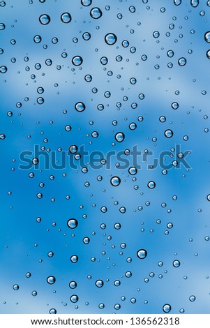 Droplets of water on windscreen with blue sky in background after raining