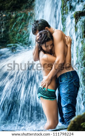 Couple hugging and kissing under waterfall