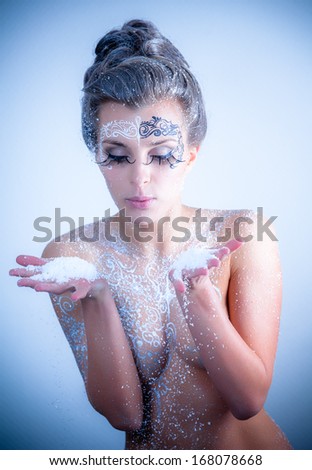 Beautiful sexy, glamorous girl with drawings on the body in an image of the queen of winter. Blue toning