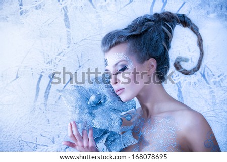 Beautiful sexy, glamorous girl with drawings on the body in an image of the queen of winter. Blue toning