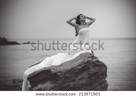 Attractive woman in white fabric on the rock