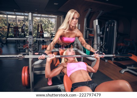 Beautiful girls in fitness club out exercise with a bar in the gym Bar Bench Press