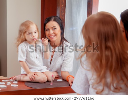 Mother and daughter in room interior near mirror