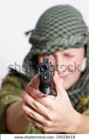 The woman soldier with a pistol in hands on a light background