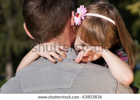 The small crying girl on a shoulder of the father
