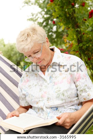 The elderly woman reads the book in a garden