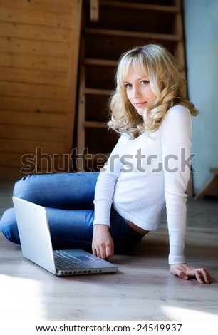 Fair-haired girl in jeans and a white blouse  with the computer