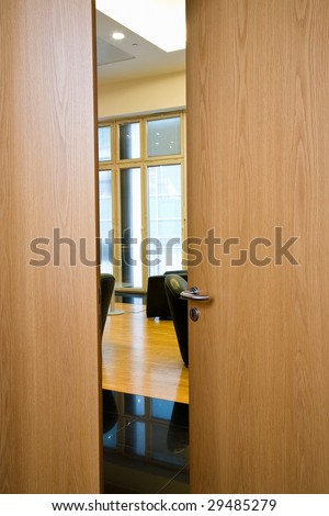 Slightly opened wooden door with the metal handle close up