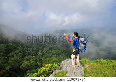 Young woman standing with backpack on cliff\'s edge