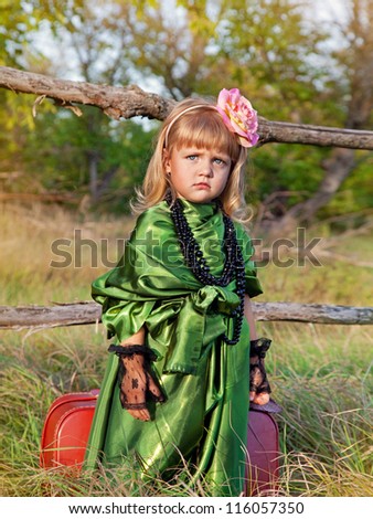 small girl with a suitcase in green dress