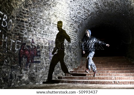 Man running trough dungeon, jumping with shadow on the wall