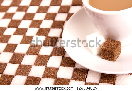 Cup of coffee with sugar on sugared background.