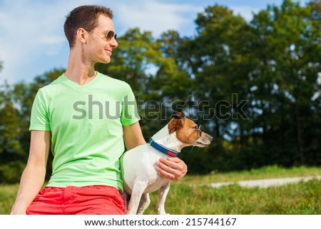 dog and owner observing together , sitting very close together having a good time outdoors