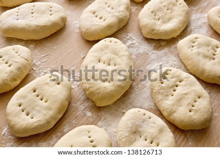 Closeup of a homemade raw patties/dough/pies prepared to fried in oil on cutting board/Raw patties