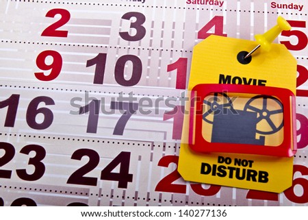 Do not disturb when movie runs concept shot. Do not disturb yellow label/tag on a paper calendar background.