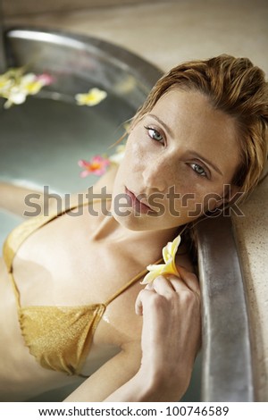 Attractive young woman bathing in a bath of flowers in a health spa.