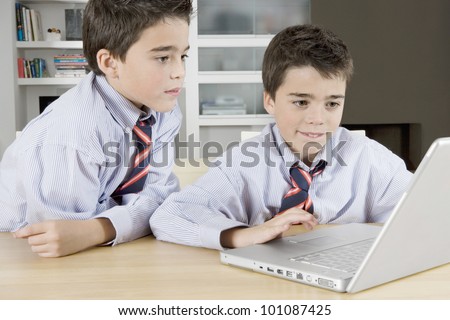 Two twin brothers sharing a laptop computer at home.