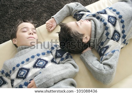 Two identical twin brothers sleeping on a sofa in the living room.