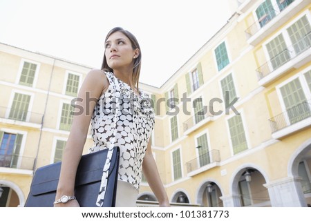 Dynamic businesswoman walking through a European city\'s square, turning back.