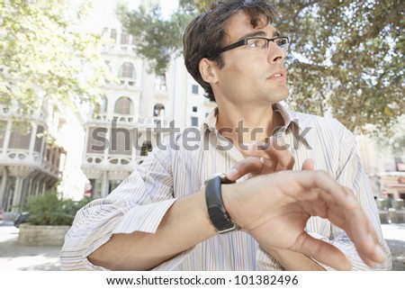 Attractive businessman looking at the time while rushing in the city.
