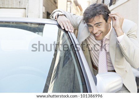 Young businessman grooming himself in the mirror of a parked car in the city.