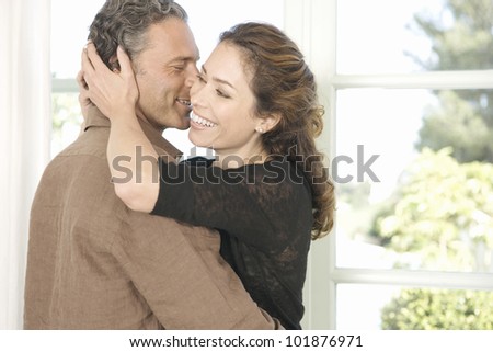 Mature man and woman hugging and whispering in each other\'s ear.