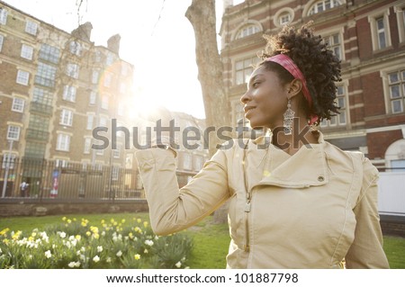 Young african american woman holding the sun in her hand at sunset in the city of London.
