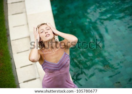 Over head view of a woman by a swimming pool under falling rain in the summer.