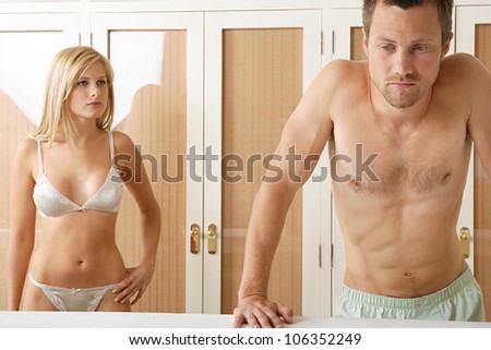 Young couple unhappy with their relationship, standing by bedroom\'s wardrobe.