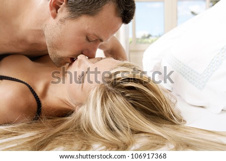 Young couple passionately kissing in bed.