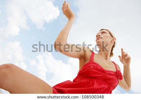 Under view of an attractive woman practicing martial arts against a blue sky.