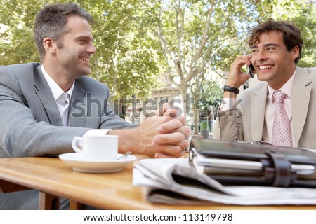 Two businessmen having a meeting in a coffee shop terrace outdoors.