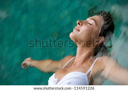 Close up profile view of a young woman floating in water while in a swimming pool on vacation.