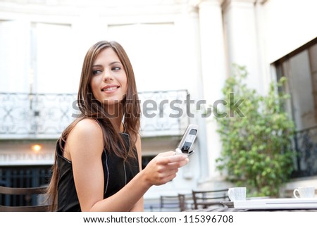 Portrait of a beautiful businesswoman using a cell phone while sitting in a classic coffee shop, smiling outdoors.
