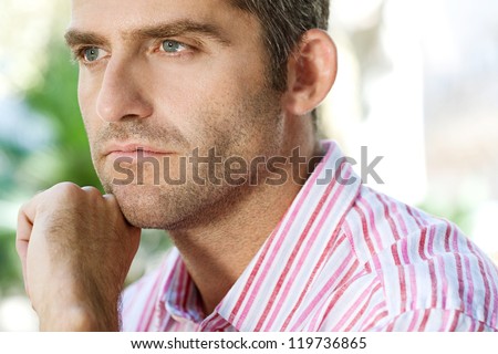 Close up portrait of a senior businessman resting his chin on his hand in the city.