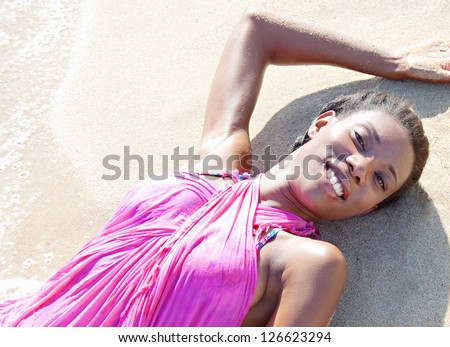Over head beauty portrait of a black woman relaxing on a beach shore, bathing in the waves on golden fine sand.